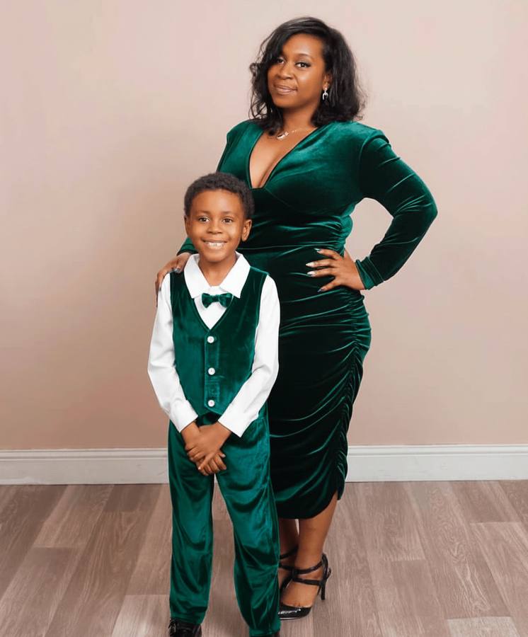 Raven in an emerald velvet dress with Khaza beside her in a matching green vest.